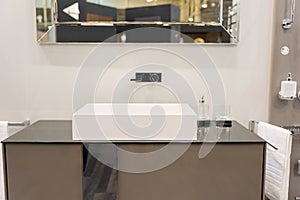Modern square washbasin with tap mounted to wall under the mirror