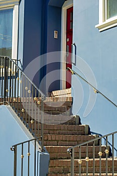 Modern staircase with black metal hand rails and steps with blue stucco building facade or exterior on house or home