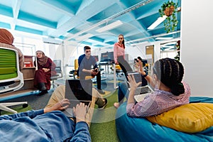 In a modern startup office, a diverse group of young and capable businesspeople engage in lively discussions about