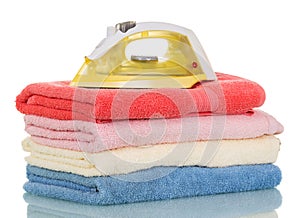 Modern steam iron and stack of towels isolated on white.