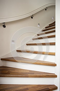 Modern steel staircase with wooden steps in a new apartment in a residential building with spots light in wall