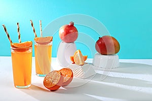 Modern still life with citrus, orange juice and ingredients on colored bright background with long hard shadows, minimal detox