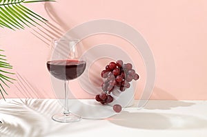 Modern still life with red wine, margarita alcoholic cocktail and grapes on a pastel background with long hard shadows, minimal