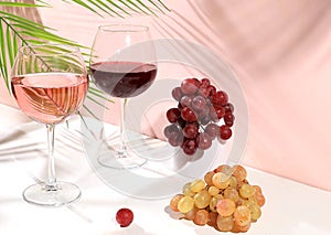 Modern still life with white and red wine, alcoholic margarita cocktail and grapes on pastel background with long hard shadows,