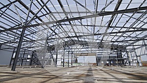 Modern storehouse construction site, structural steel structure of new commercial building against. Construction of