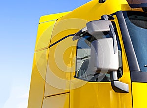 Modern, streamlined truck cab with good aerodynamics with a rearview mirror. Yellow truck cab, background