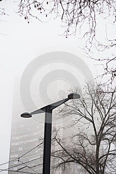 Modern street lamp with europe tower on background by foggy day