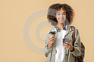 Modern student hipster has coffee break after lectures. Cheerful african american woman with wireless headphones photo