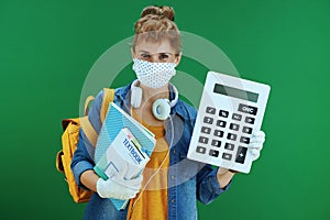 Modern student woman showing big calculator isolated on green