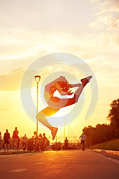 Modern style dancer woman jumping. Dancer silhouette at sunset. Contour of girl on urban city background