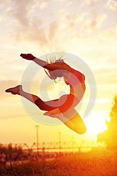 Modern style dancer woman jumping. Dancer silhouette at sunset. Contour of girl on urban city background