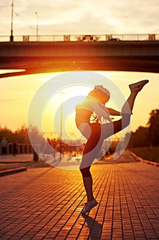 modern style dancer woman jumping. Dancer silhouette at sunset. Contour of girl on urban city background