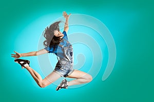 Modern style happy girl dancing on fresh blue background. Hip Hop dancer jumping concept.