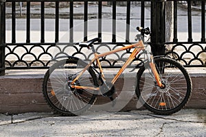 Modern style mountain bicycle locked by the fence in city street in the city