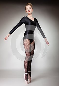 Modern style woman ballet dancer full length on gray