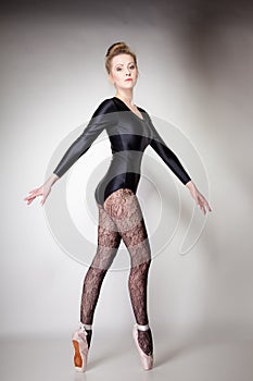 Modern style woman ballet dancer full length on gray