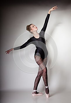 Modern style woman ballet dancer full length on gray