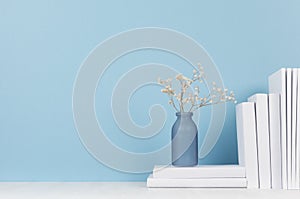 Modern style workplace - white stationery and glass vase with dry flowers on soft blue background and light desk.