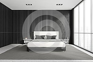 Modern stylish bedroom interior with wooden walls, concrete floor, master bed and panoramic window city view. Skyscraper building