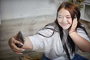 Modern Stylish chubby student brunette girl taking selfie with cell mobile phone. Picture of attractive young brunette