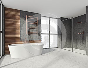 Modern stylish hotel bathroom interior, with ceramic bathtub, shower cabin. Grey wall, concrete floor. Panoramic window. City view