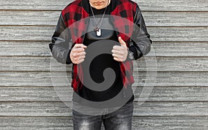 Modern stylish young man in a checkered stylish jacket in gray ripped jeans in a t-shirt is posing in the city