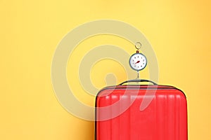 Modern suitcase and hanging scales against color background