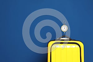 Modern suitcase and hanging scales against color background