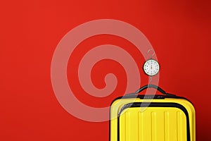 Modern suitcase and hanging scales against color background