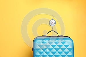 Modern suitcase and hanging scales against color background