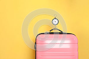 Modern suitcase and hanging scales against color background