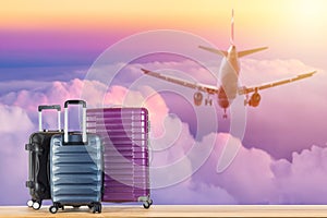 Modern suitcases baggage for travelling or business trip on wooden floor against landing airplane sunset sky background