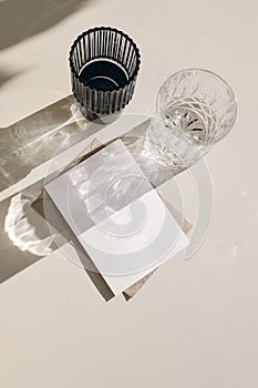 Modern summer drinks still life. Glasses of water, cocktails in sunlight. Long harsh shadows. Beige table background