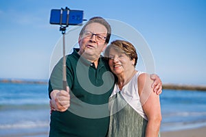 Modern sweet and loving hispanic mature couple taking selfie portrait- senior retired husband and wife on their 70s enjoying beach