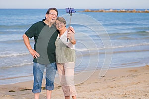 Modern sweet and loving mature couple taking selfie portrait- senior retired husband and wife on their 70s enjoying beach walk