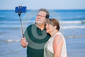 Modern sweet and loving mature couple taking selfie portrait- senior retired husband and wife on their 70s enjoying beach walk