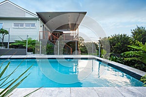 Modern swimming pool with blue water beside a house