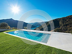 Modern swimming pool in the garden with lake and valley view