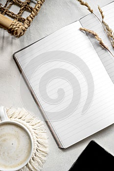 Modern tabletop with with open notebook mockup, cup of coffee, dried plants. Flat lay, minimal style workspace