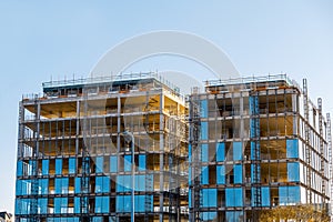 Modern tall building construction site. Metal frame and a lot of glass. Blue cloudy sky. Building new residential and office space