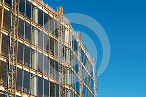 Modern tall building construction site. Metal frame and a lot of glass. Blue cloudy sky. Building new residential and office space