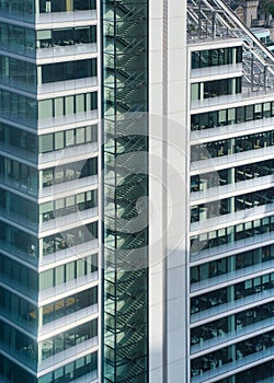 Modern tall steel and glass office building, closeup detail to regular windows, staircase visible