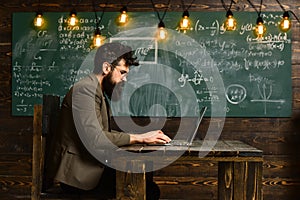 Modern teacher hipster writing on big blackboard with math formula, E-Learning concept with student holding his modern