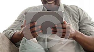 Modern technologies for leisure. Black mature man using digital tablet, surfing internet or having video call, crop