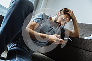 Depressed handsome man using his smartphone