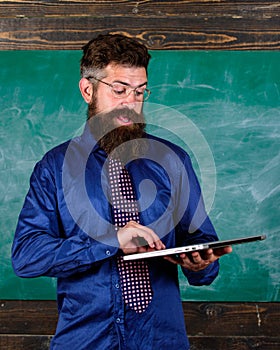 Modern technology education. Start lesson. Teacher bearded man with modern laptop chalkboard background. Hipster teacher