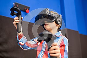 Modern technology, gaming and people concept - boy in virtual reality headset or 3d glasses playing videogame at game