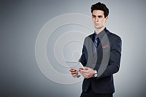 Modern technology made succeeding inn business easier. a young businessman using a digital tablet against a grey