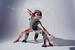 Modern teen contemporary dancer poses in front of the studio background.