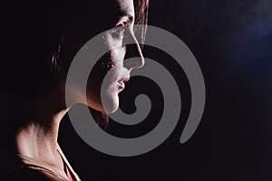 Modern teen contemporary dancer poses in front of the studio black background.